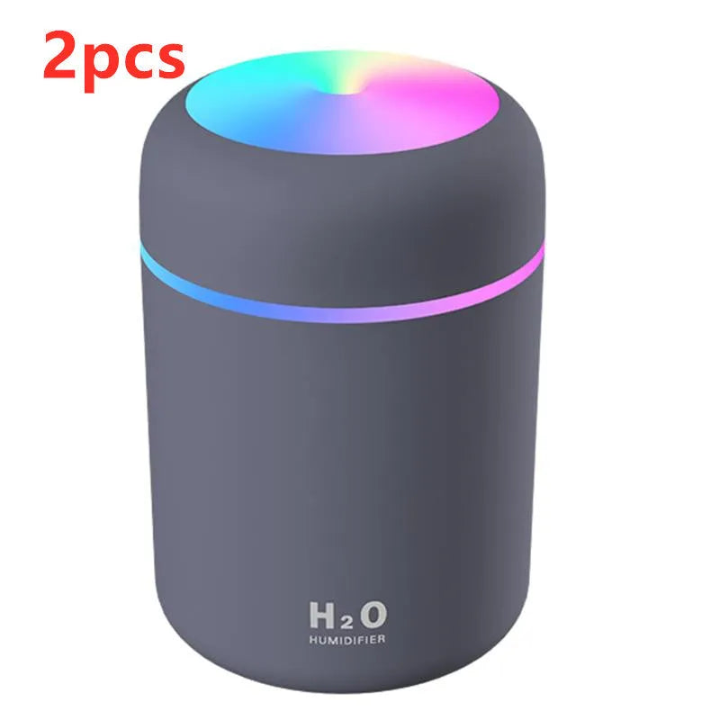 Pink USB desktop humidifier with coloured lights and water tank on a wooden desk