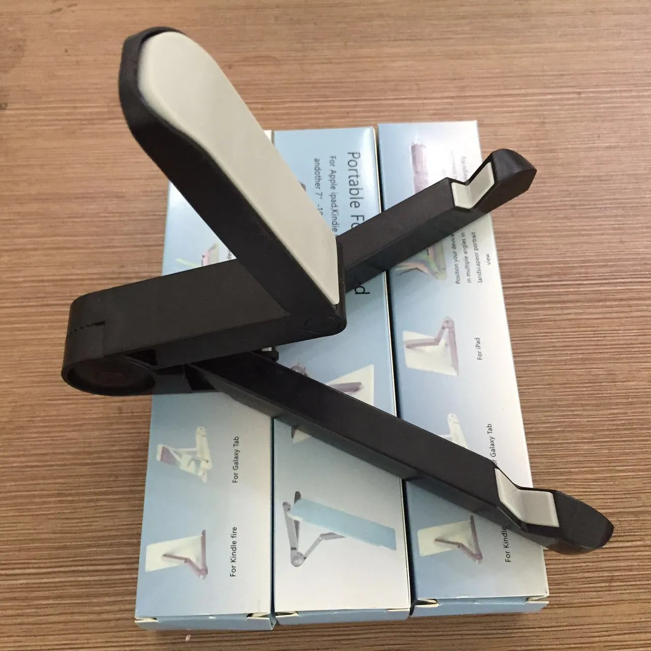 Black foldable tablet holder holding a smartphone in landscape mode on a desk.