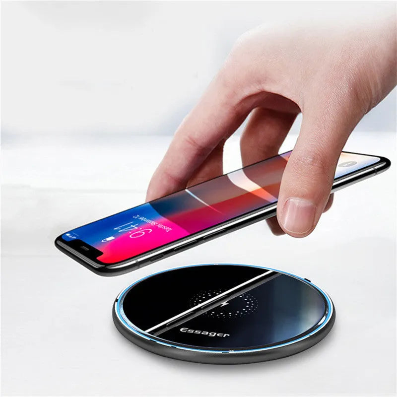 Black aluminium alloy Qi wireless fast charging pad for phones on a wooden desk.