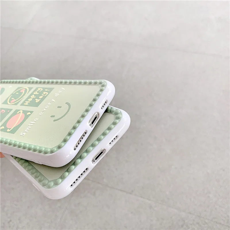 Green TPU iPhone case with geometric smiley face and polka dot frame design on a table.