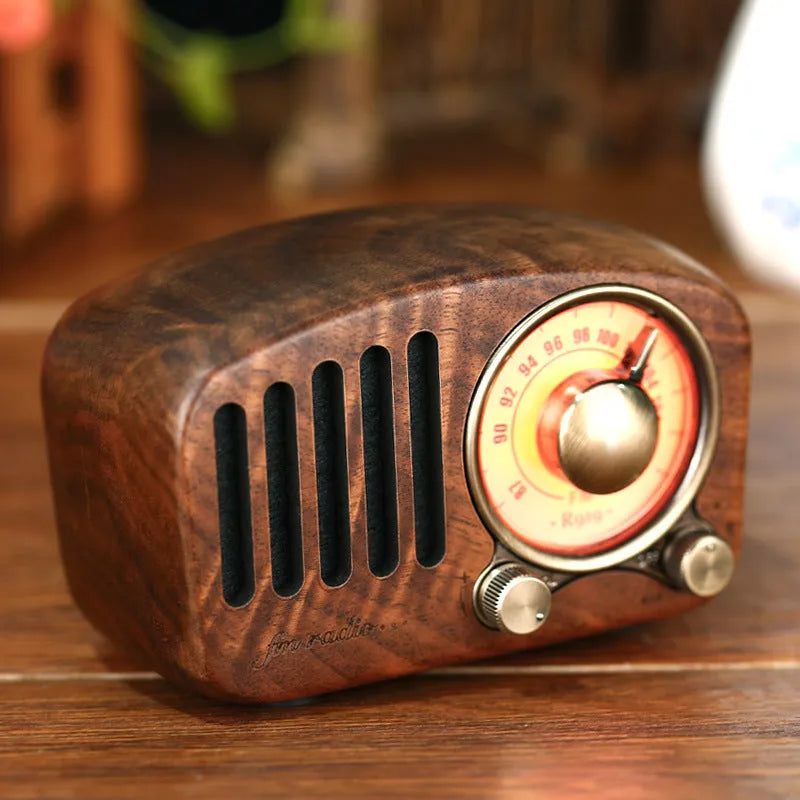 Compact retro wooden wireless Bluetooth speaker in cherry wood finish on a wooden table