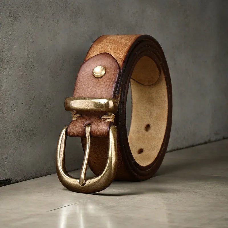 Men's black genuine cowhide leather belt with copper pin buckle on a jeans background.