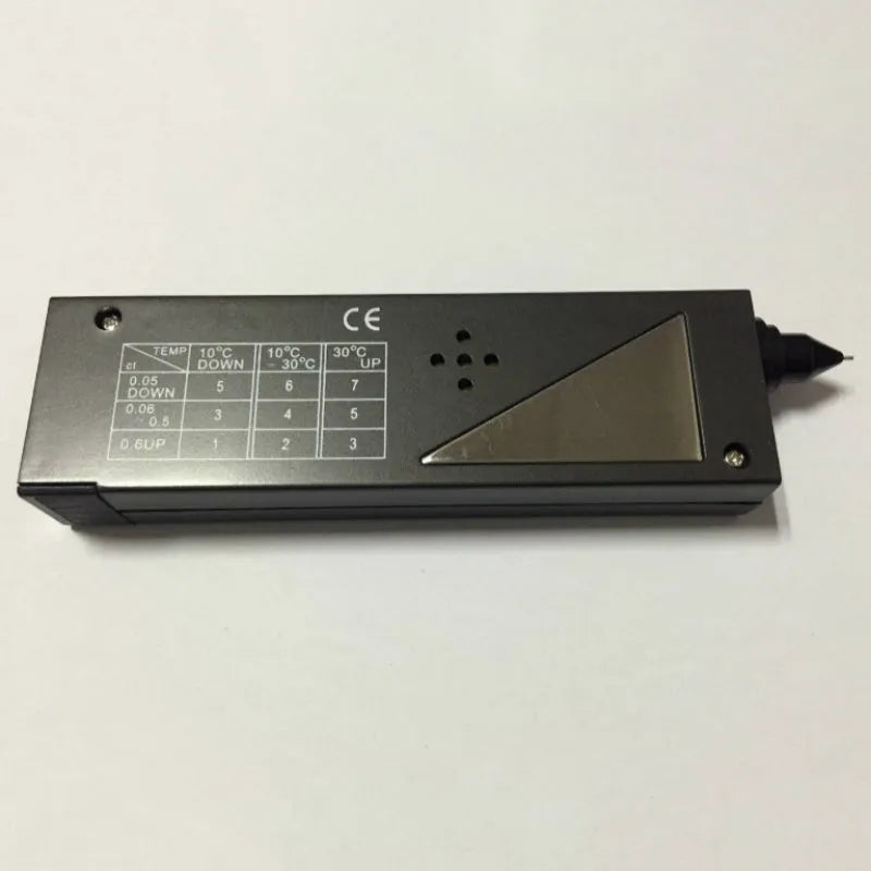 Handheld black diamond thermal conductivity tester with metal probe on a gemstone.