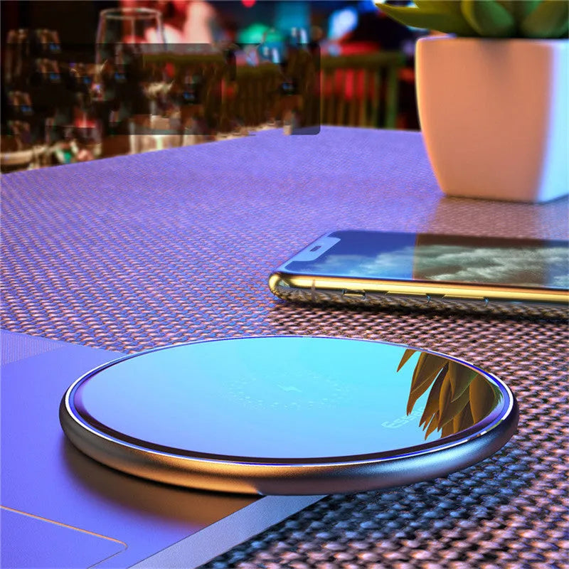 Black aluminium alloy Qi wireless fast charging pad for phones on a wooden desk.