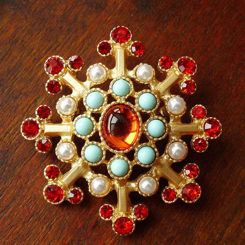 Close-up of a vintage baroque style zinc alloy brooch with a diamond shape on a dark fabric background.