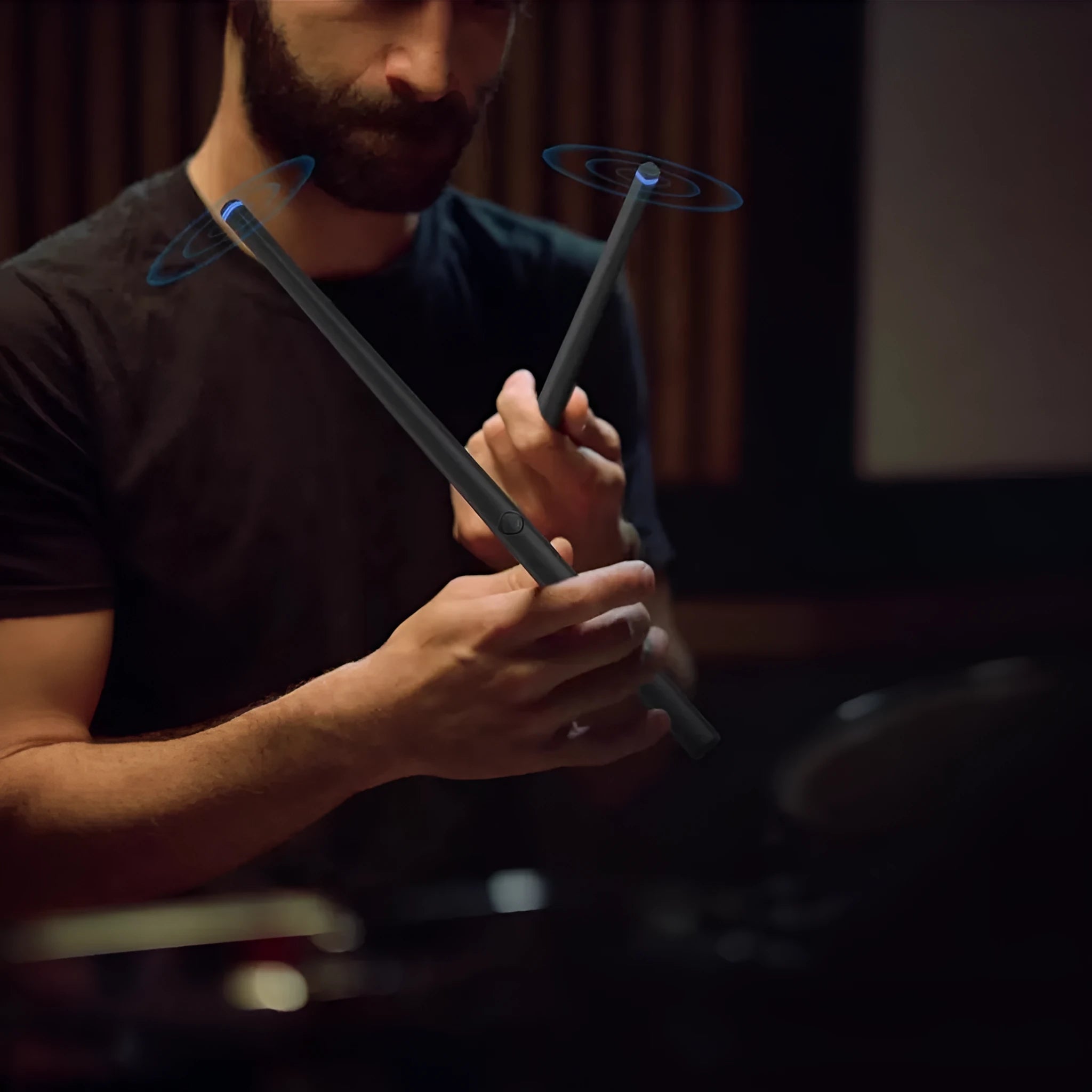 Black somatosensory air drum kit host unit with two drumsticks on a table, showing LED lights.
