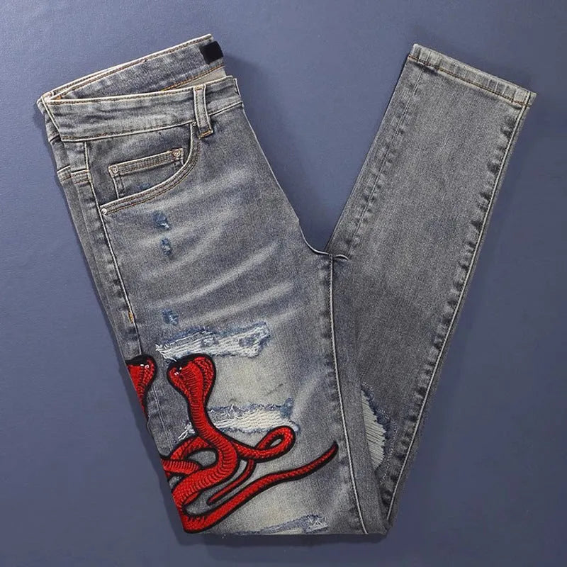 Slim fit jeans with washed-out old colour, distressed holes, and embroidered patches on cotton fabric