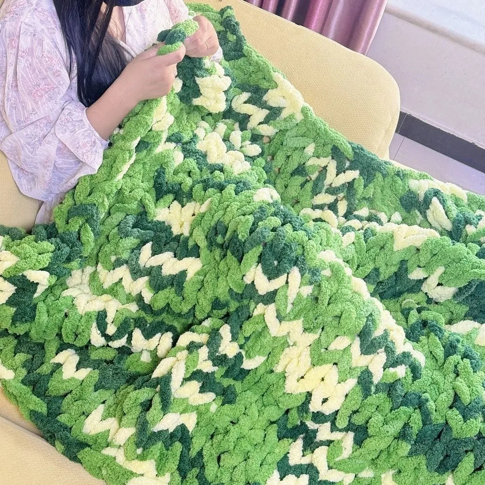 Coarse yarn chenille knitted blanket with braided gravity trim in a modern colour on a bed.