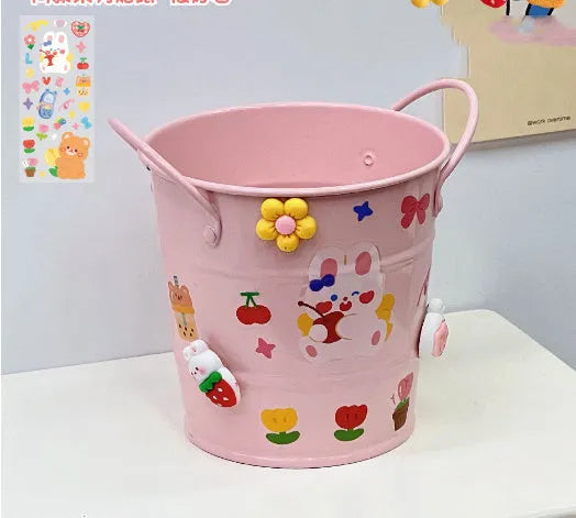 Round metal Creative Iron Art pen holder shown in pink, green, red, white, and yellow colour options on a desk.