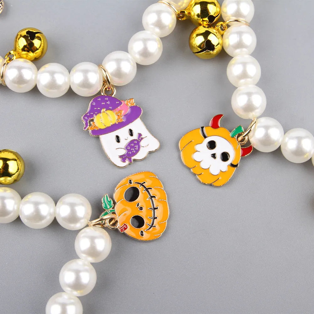 Close-up of a simulated pearl cat collar with a detailed Halloween pumpkin charm, showing the purple ghost design variant.