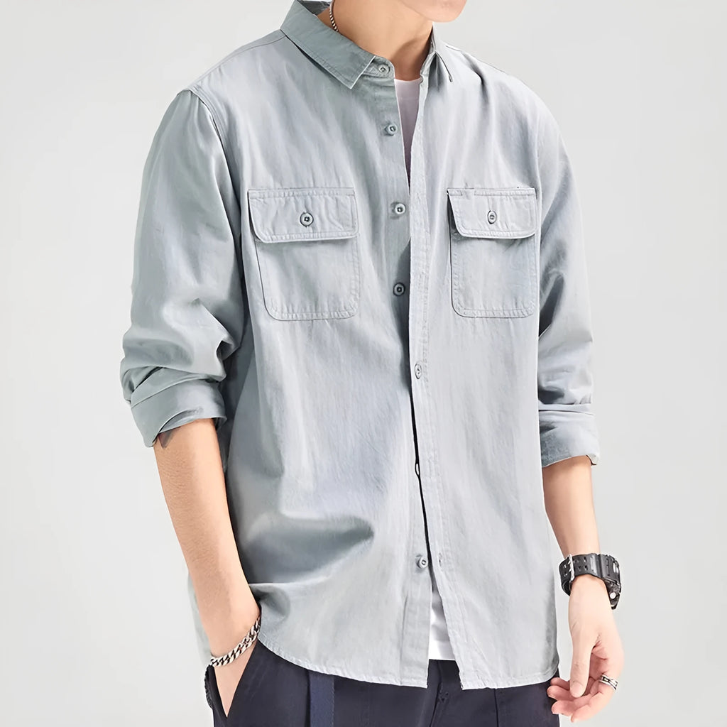 Man wearing a loose grey cardigan-style button-up shirt with long sleeves.
