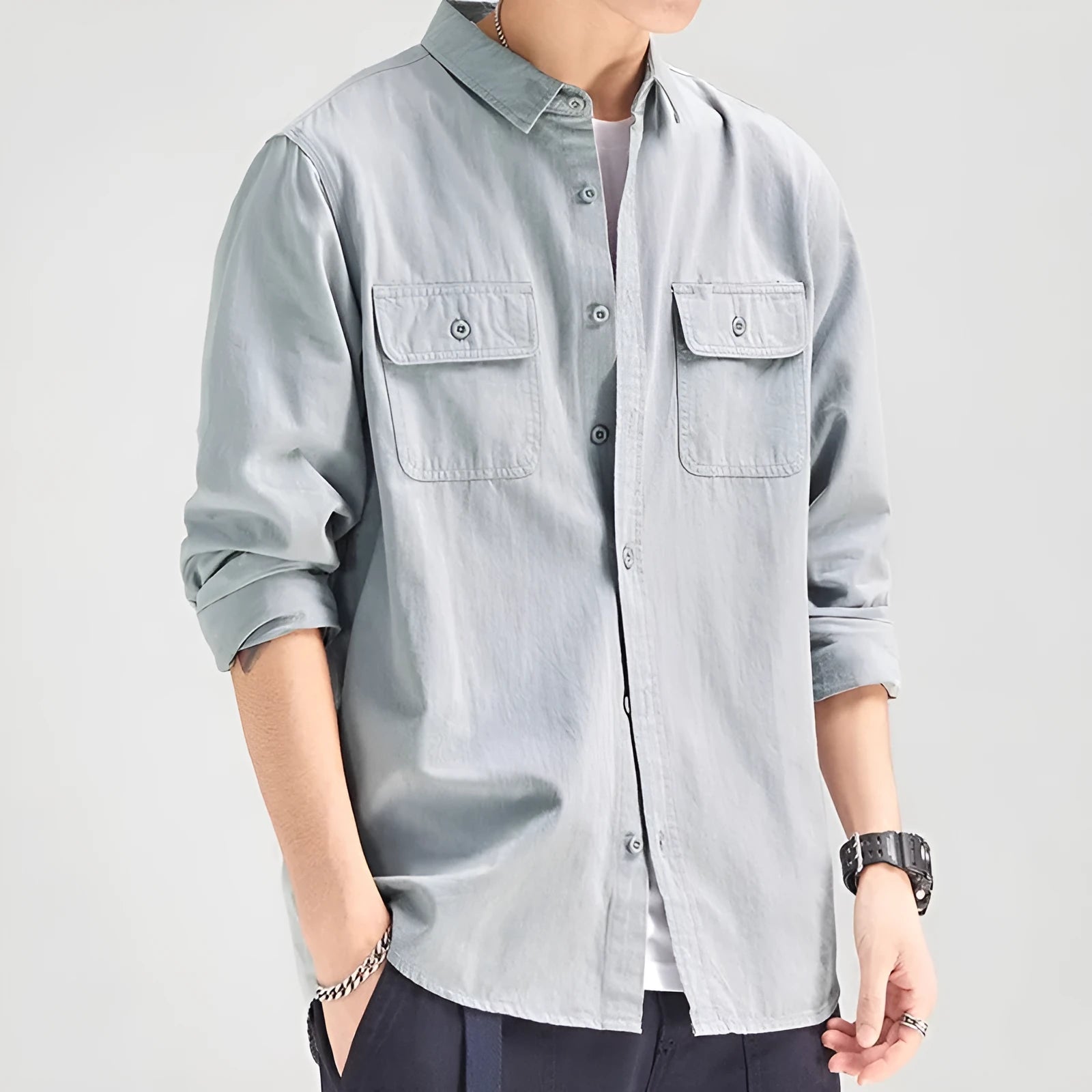 Man wearing a loose grey cardigan-style button-up shirt with long sleeves.