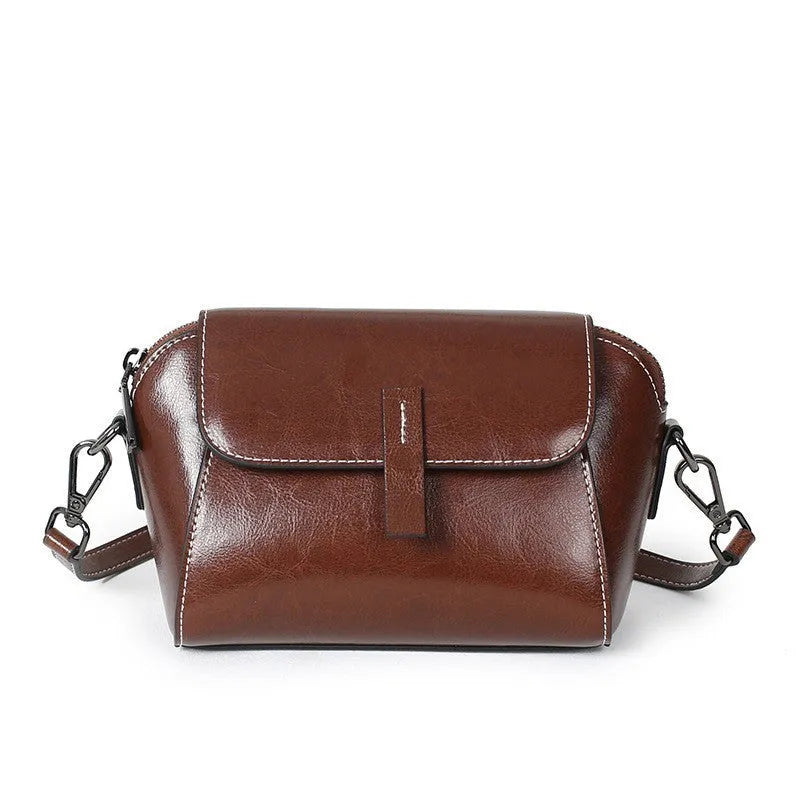 Brown genuine leather women's messenger bag with cross-body strap showing internal zipper compartments