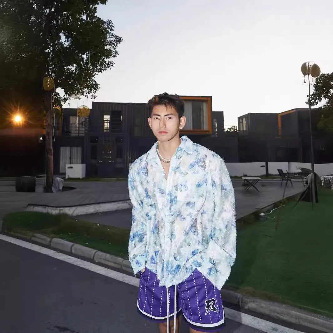 Man wearing a blue loose-fit long sleeve shirt with an embossed three-dimensional floral pattern.