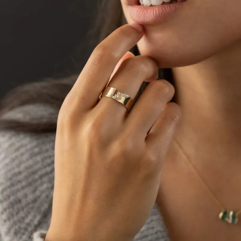 Gold-coloured copper ring with a shining zircon stone on a model's hand.