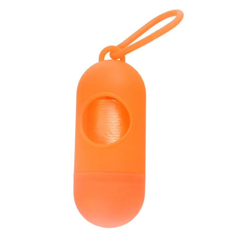 Compact black dog poop bag holder with Velcro strap and metal side hook, shown next to a roll of waste bags.