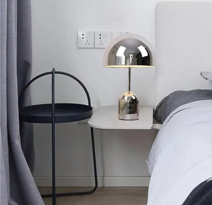 Mushroom-shaped table lamp with a metal base in rose gold finish on a wooden surface.