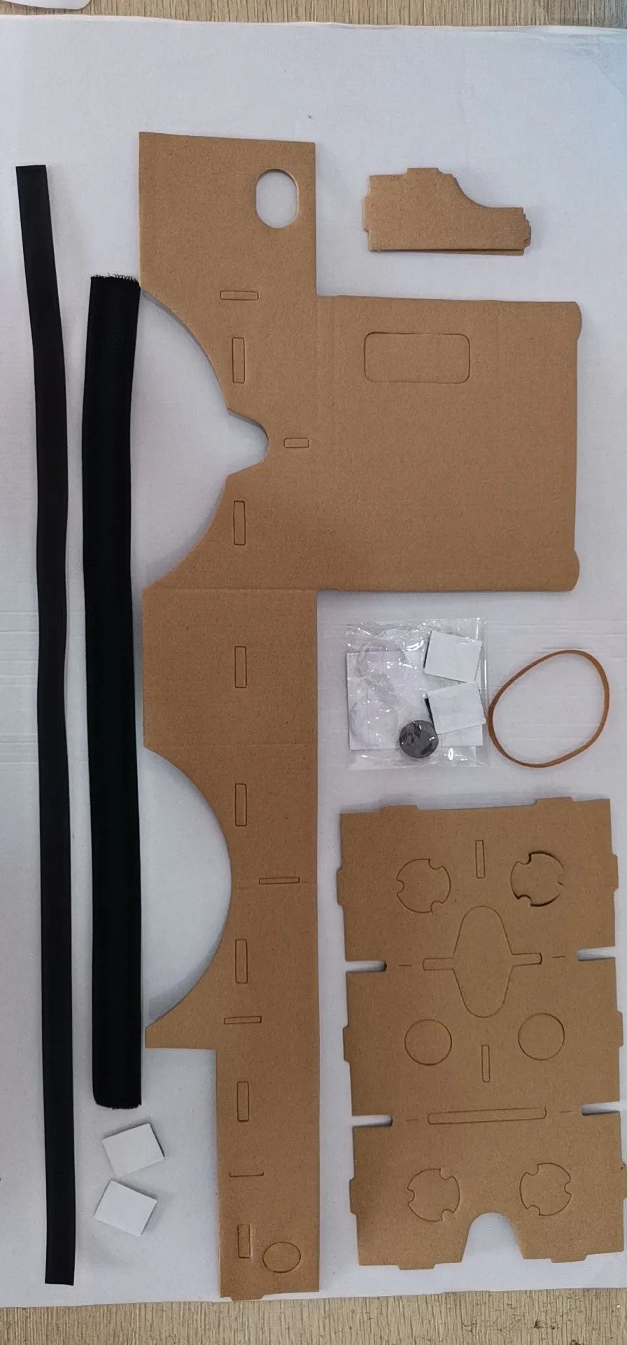 Pink and white cardboard VR headset for smartphones with adjustable strap and magnetic button.