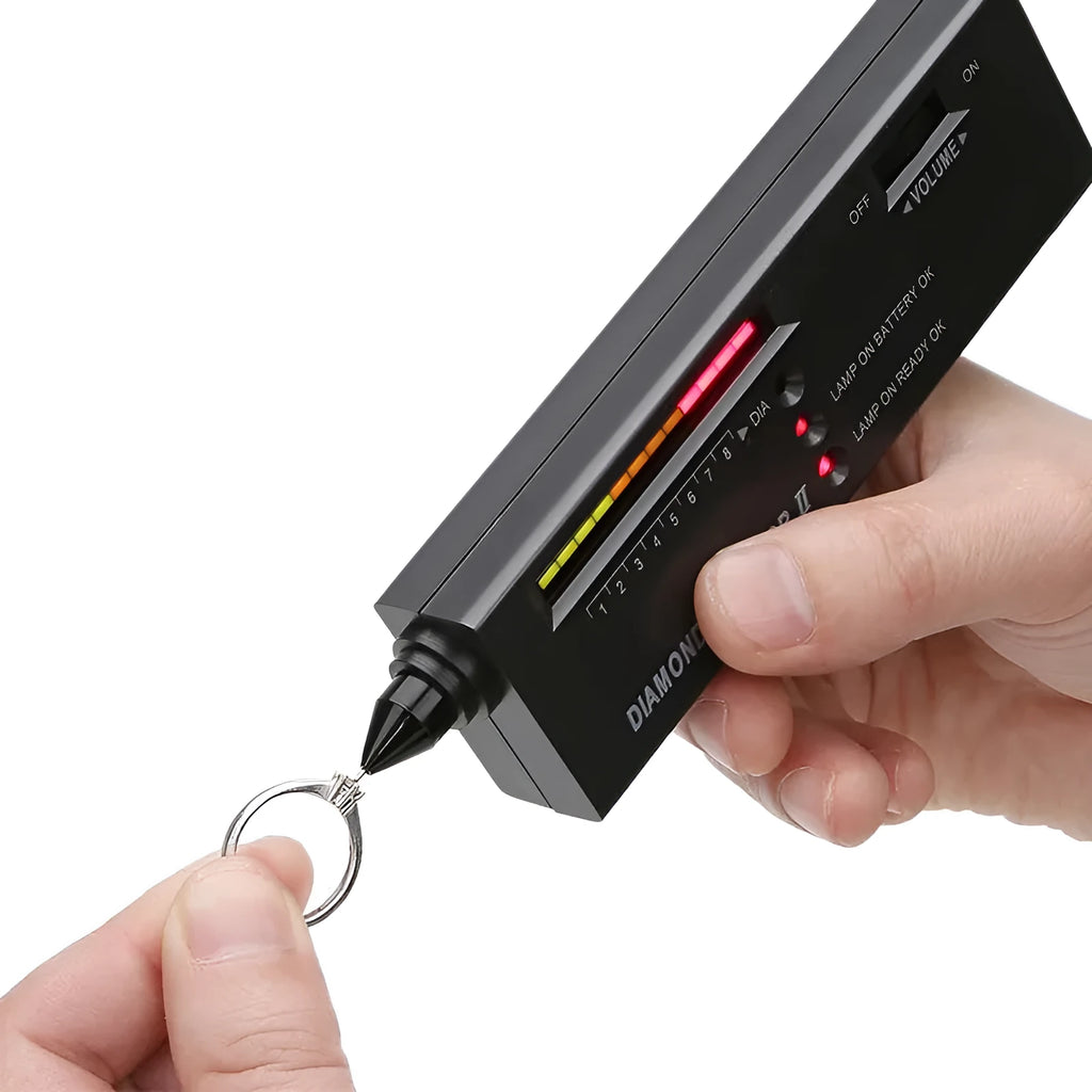Handheld black diamond thermal conductivity tester with metal probe on a gemstone.