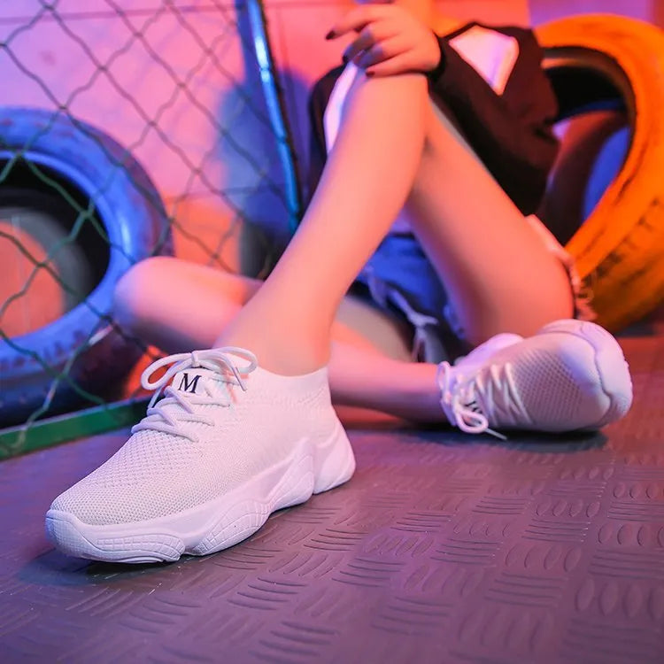Women's white sports shoes with thick rubber soles and woven upper featuring lace-up front strap