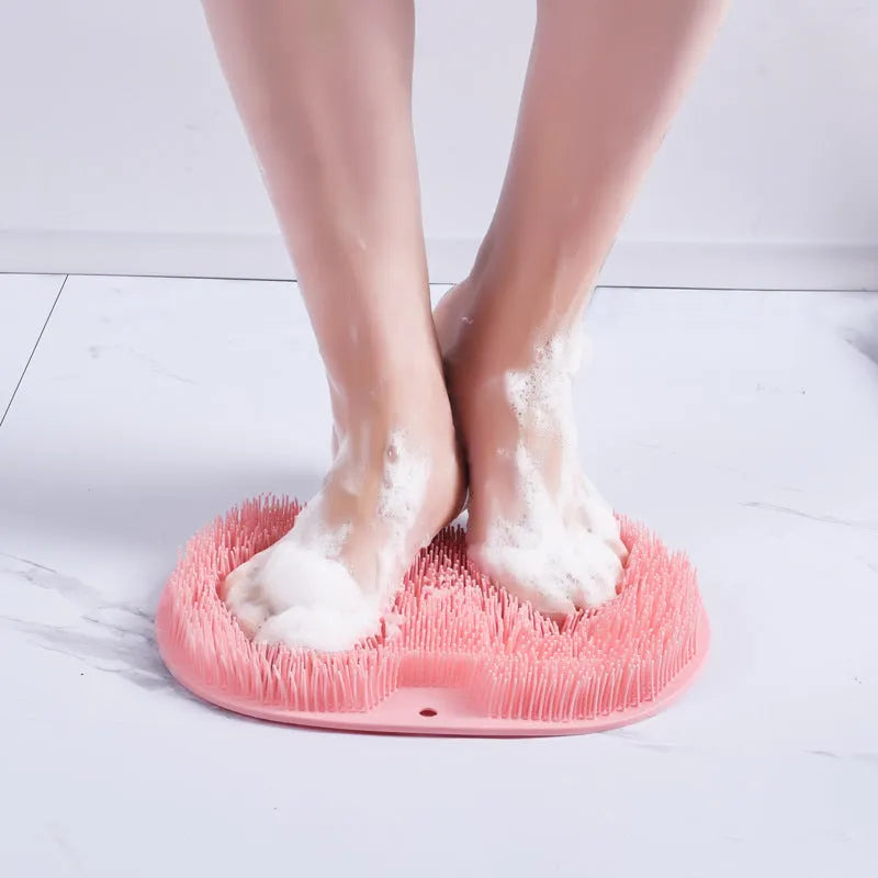 Orange silicone bath massage brush mat with suction cups on a bathroom floor