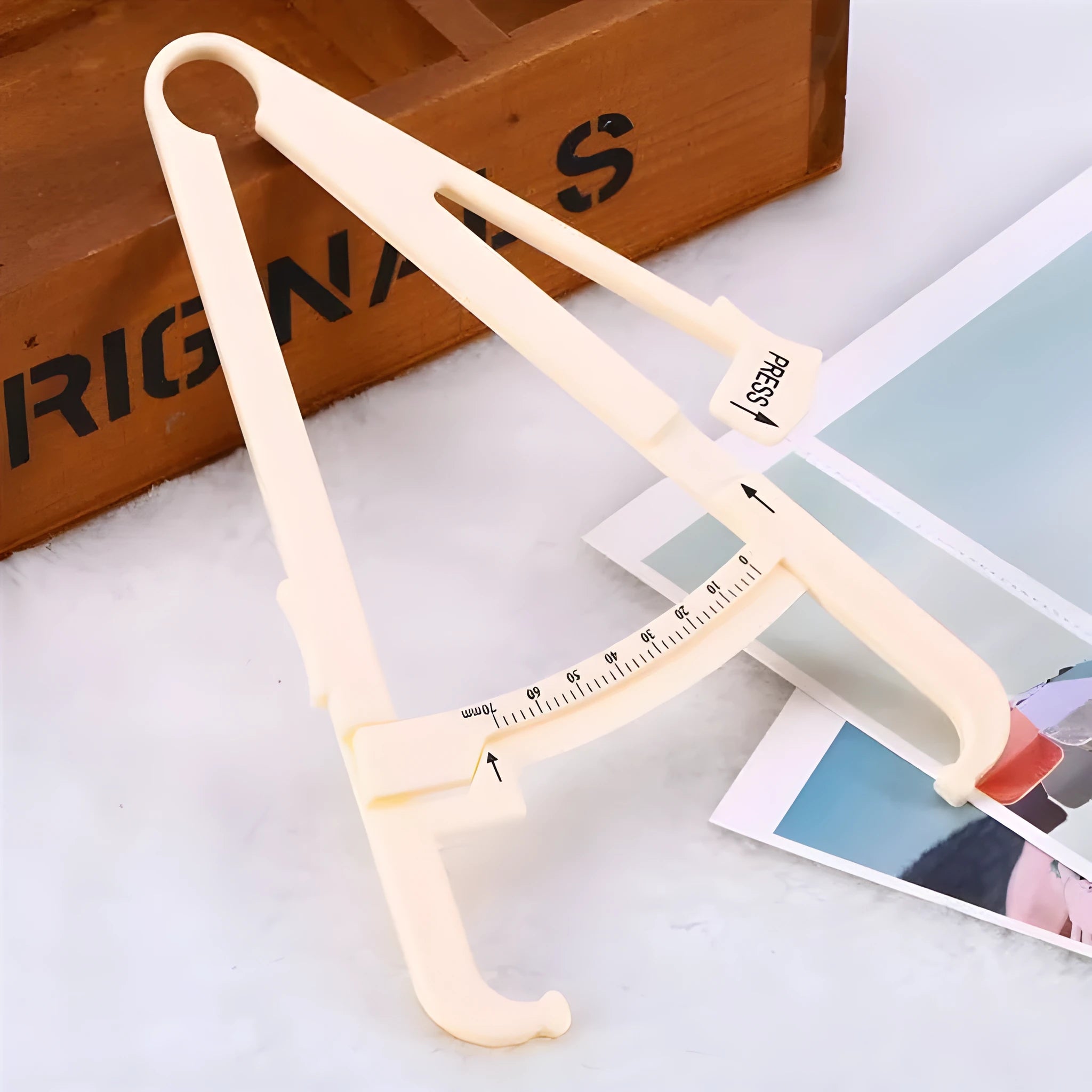 White acrylic body fat caliper with measurement scale for skinfold thickness testing.