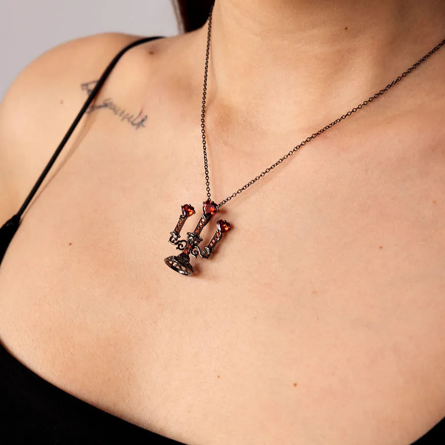Close-up of a retro-style hollow candlestick pendant necklace with a cross chain, in a gothic design.