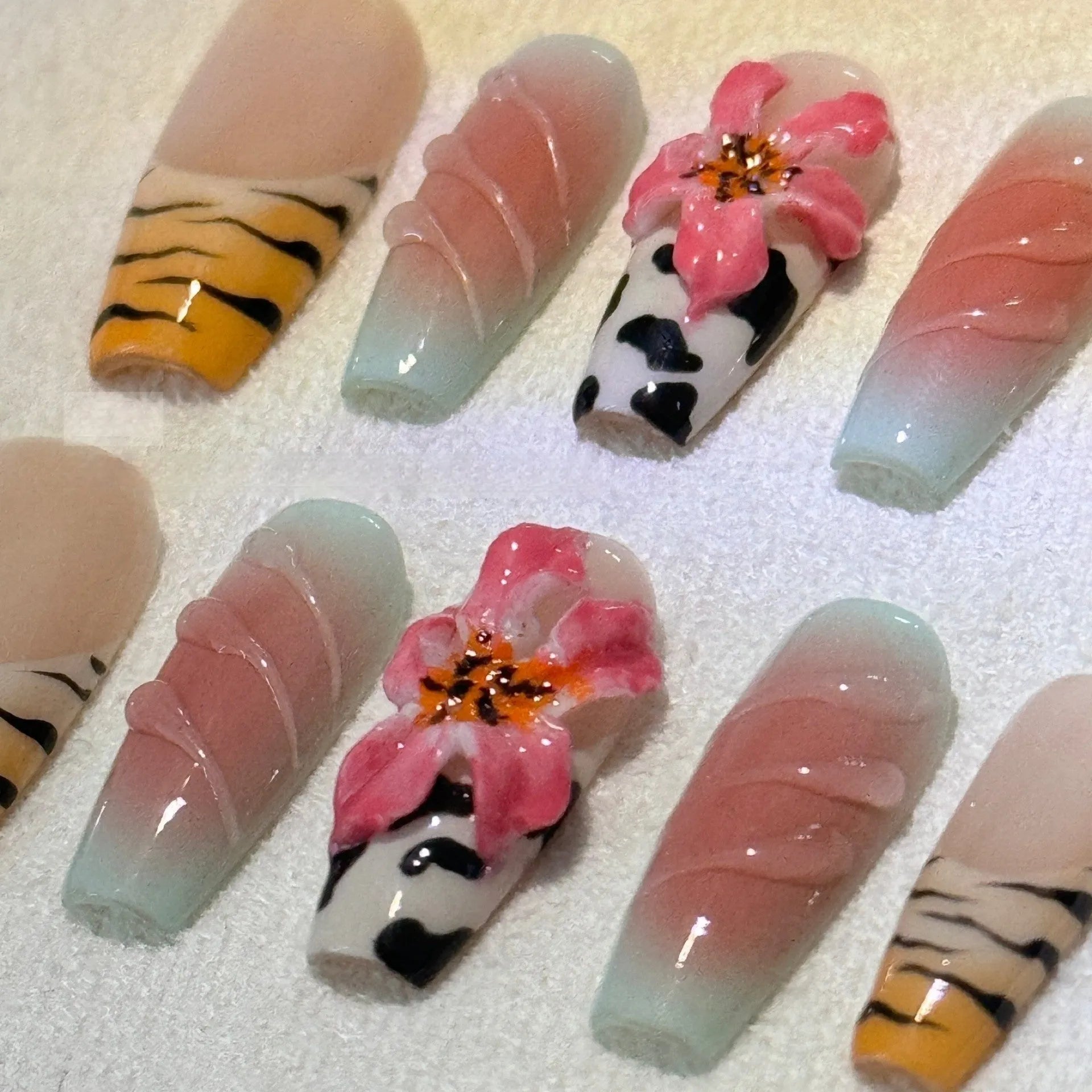 False nails with zebra pattern, carved lily design, and leopard print in long wear-resistant style.