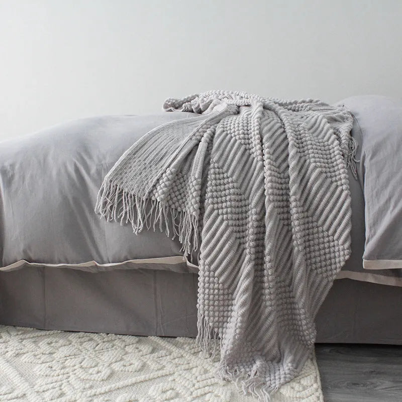 Small dark grey polyester nap blanket folded, showing its size of 127 cm by 170 cm.