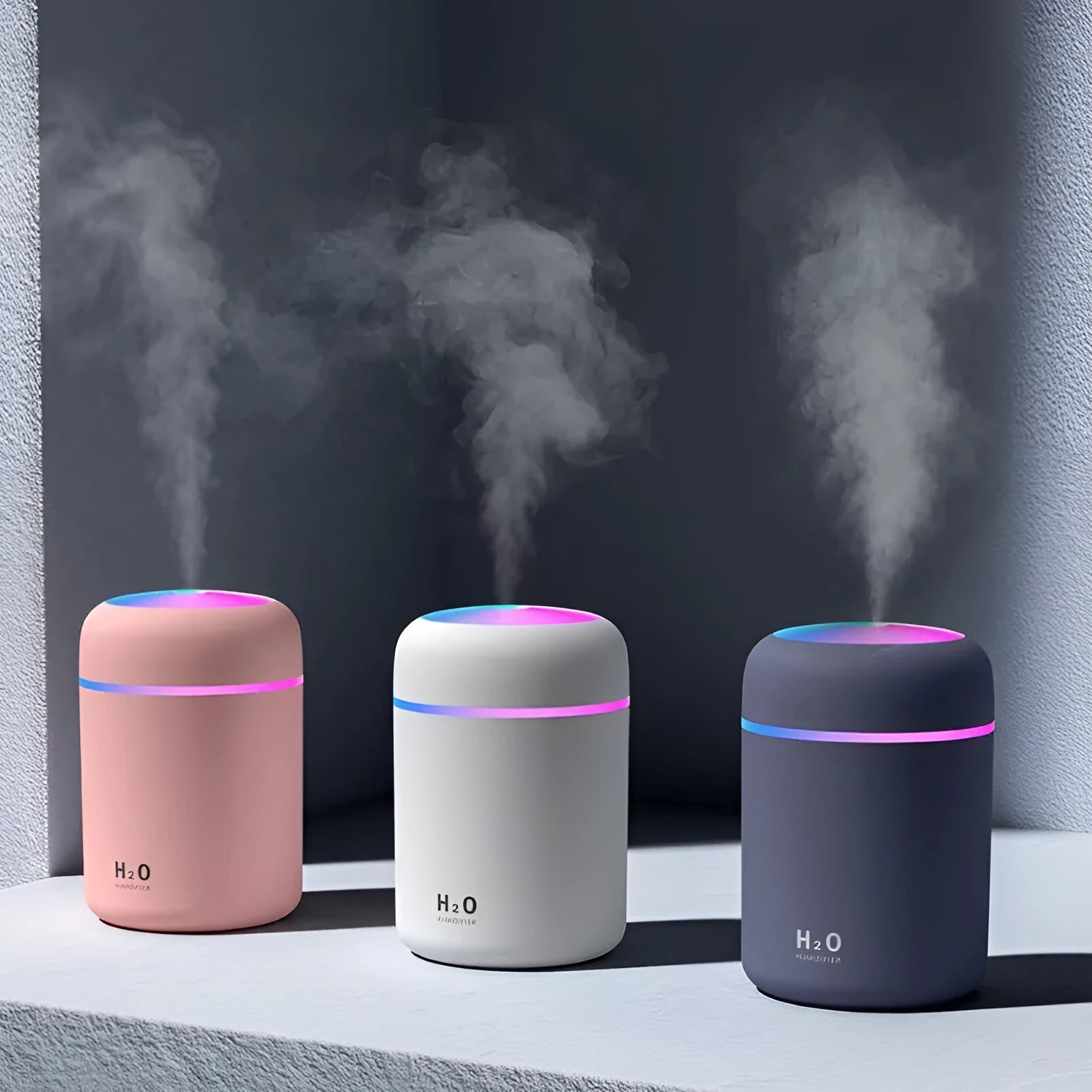 Pink USB desktop humidifier with coloured lights and water tank on a wooden desk