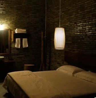 Small woven bamboo table lamp with a natural finish, shown on a wooden surface.
