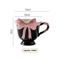 Ceramic mug with a heart and bow design in black pink and white powder colour options.