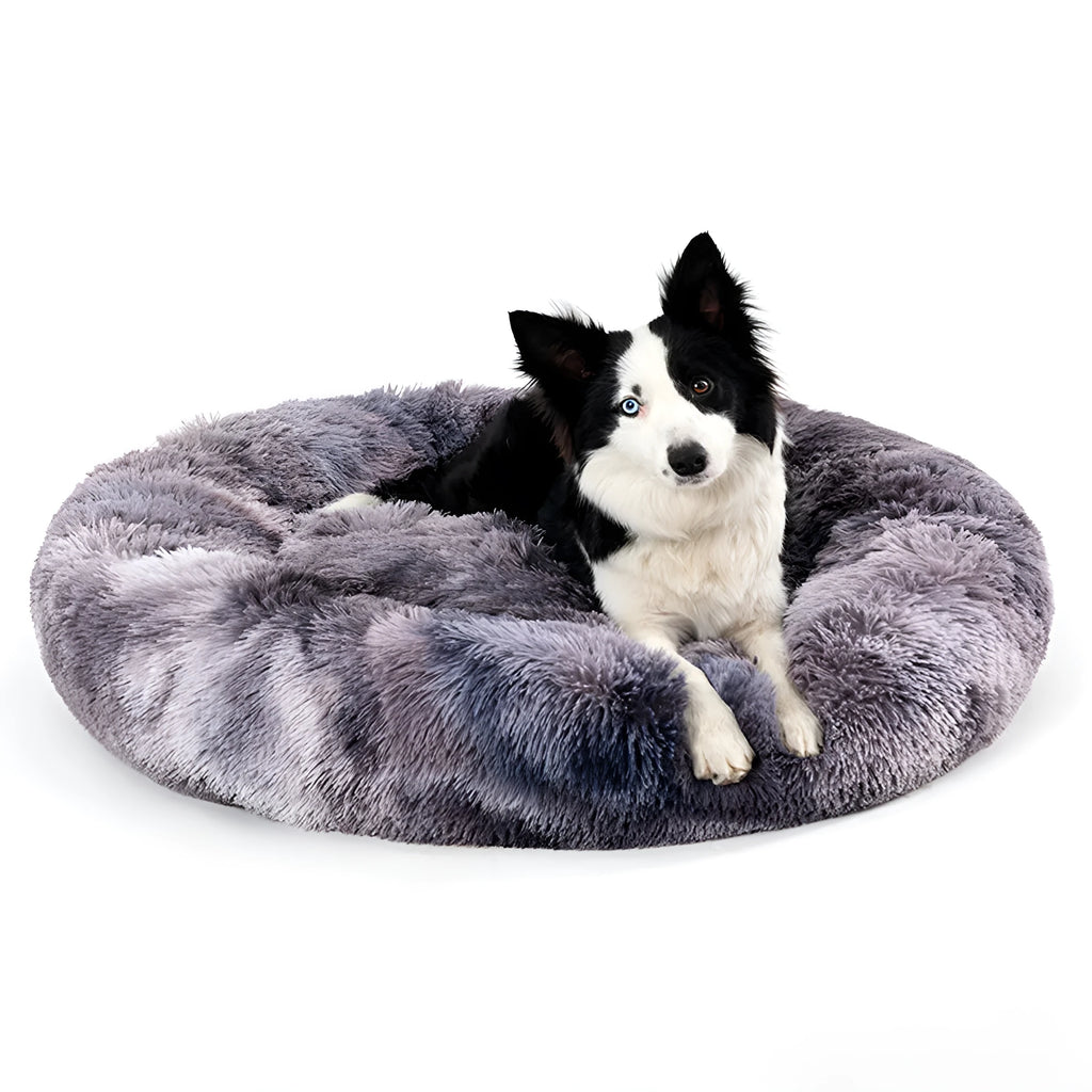 Fluffy donut-shaped dog bed in long plush fabric, shown in a light grey colour with a raised edge.