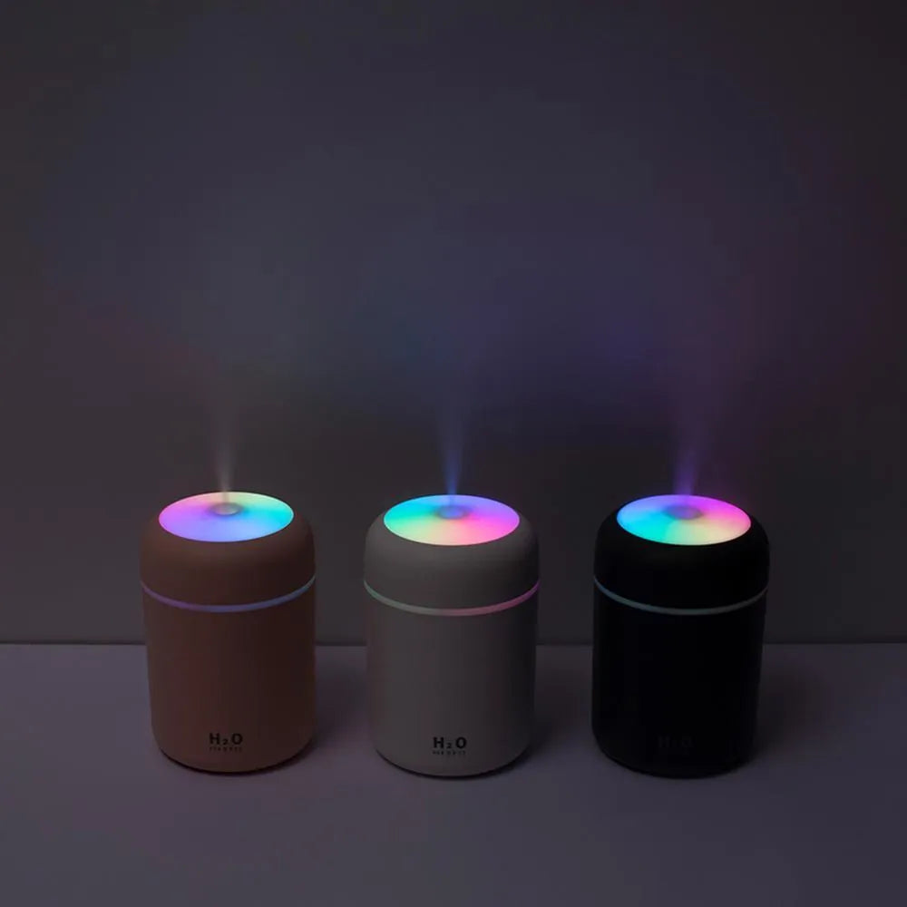 Pink USB desktop humidifier with coloured lights and water tank on a wooden desk