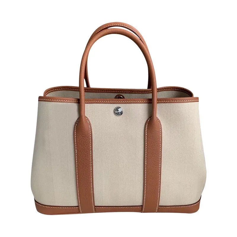 Women's canvas and leather crossbody tote bag in bucket shape with soft handles and internal zip compartments