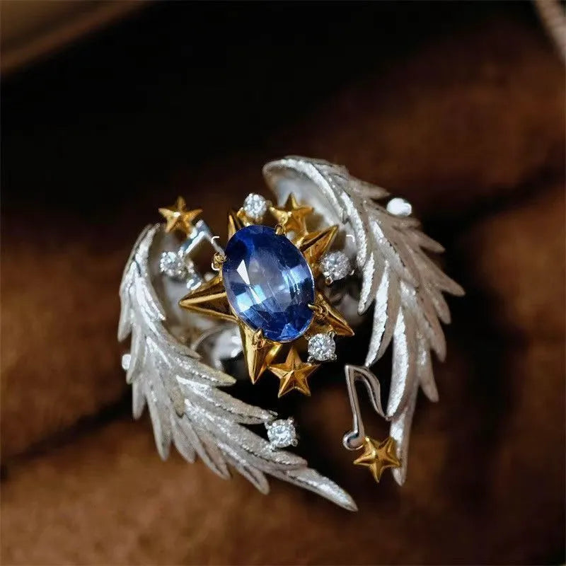 Gold-tone geometric angel wings alloy ring with adjustable opening on a finger.