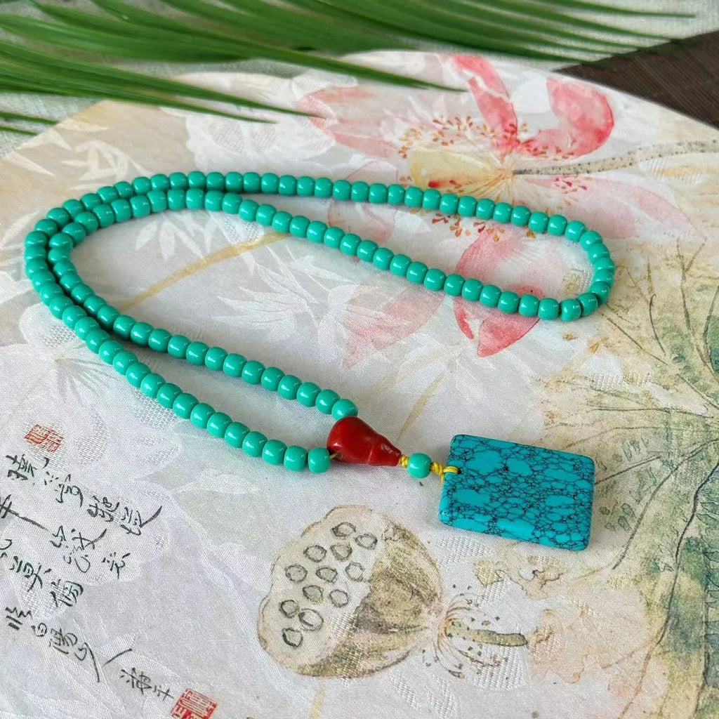 Turquoise lucky pendant necklace with hand-woven mesh flower design on ball bead chain
