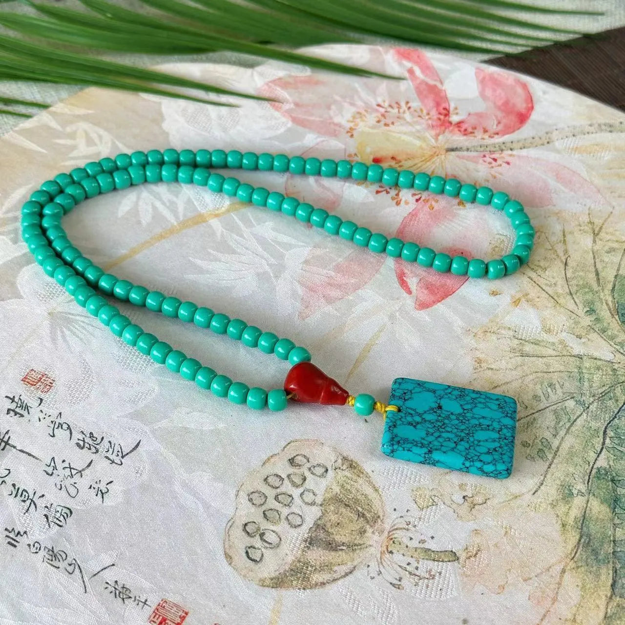 Turquoise lucky pendant necklace with hand-woven mesh flower design on ball bead chain