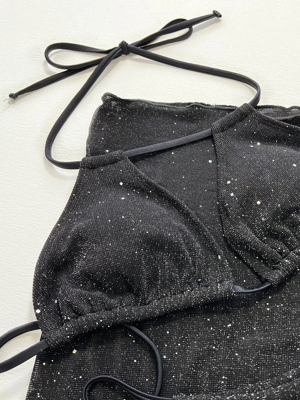 Black three-piece bikini swimsuit set with crop top and shorts on a mannequin.