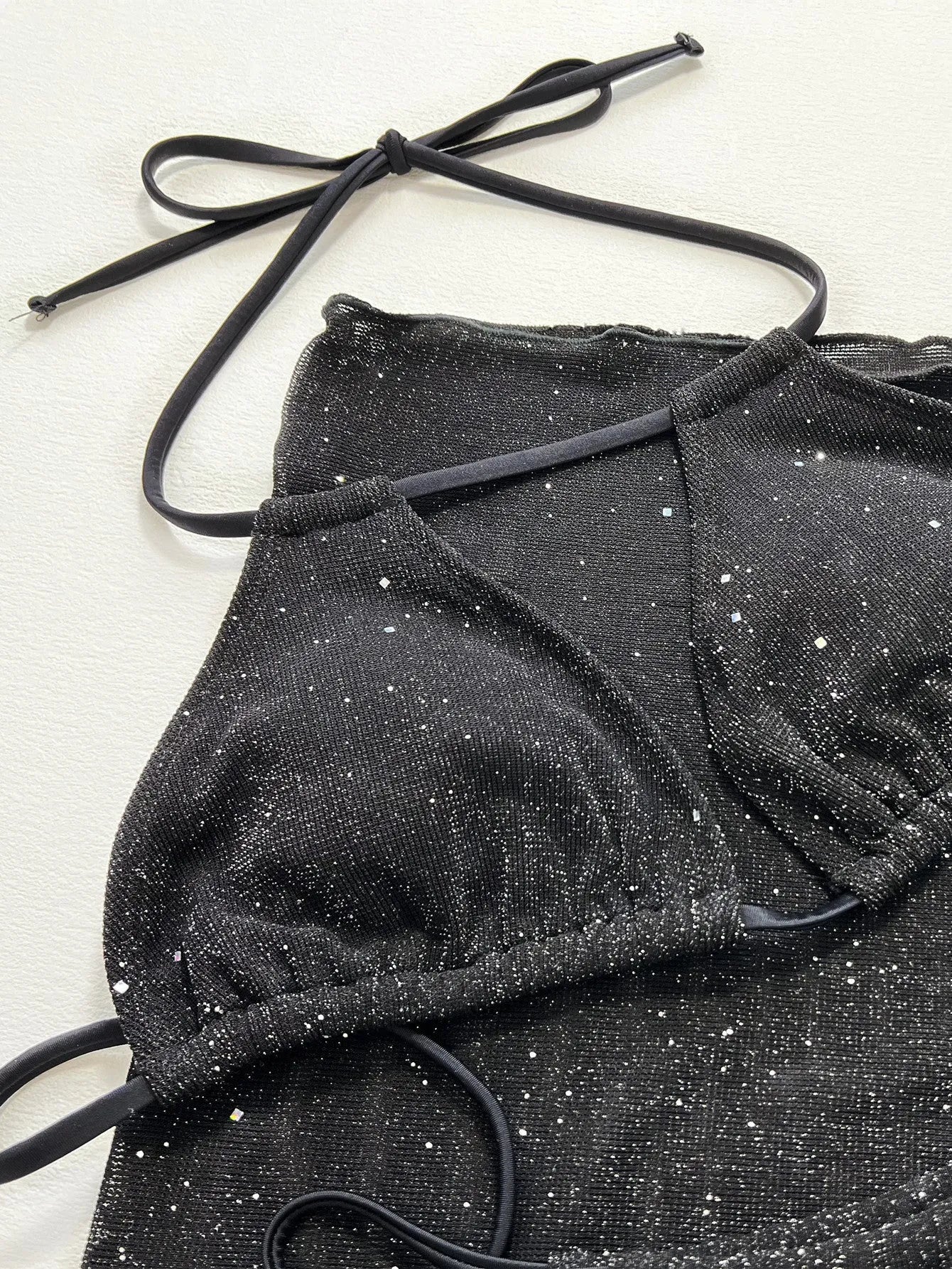 Black three-piece bikini swimsuit set with crop top and shorts on a mannequin.