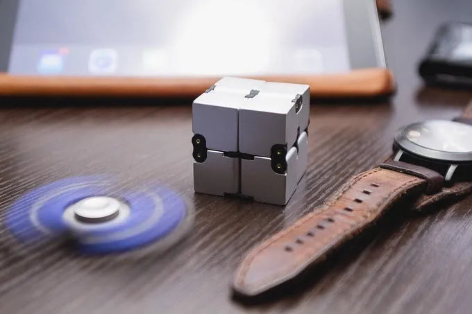 Silver zinc alloy infinity cube fidget toy with rotating segments shown on a flat surface