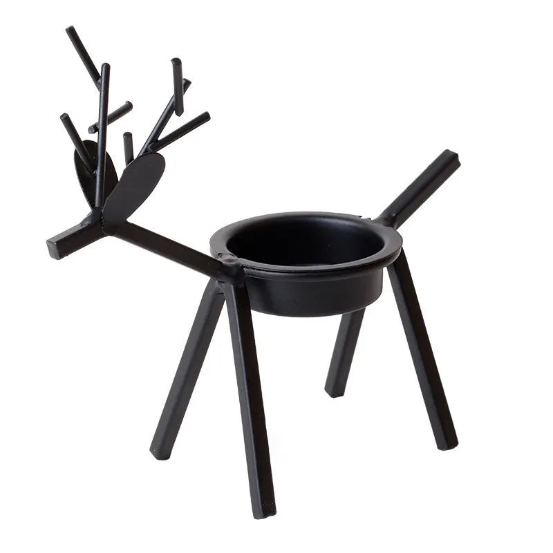 Black iron Christmas candlestick holder with decorative elk design on a table.