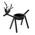 Black iron Christmas candlestick holder with decorative elk design on a table.