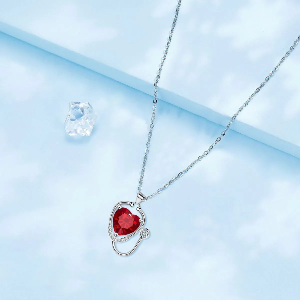 Red diamond coloured women's necklace with wings, cross, and stethoscope pendant.