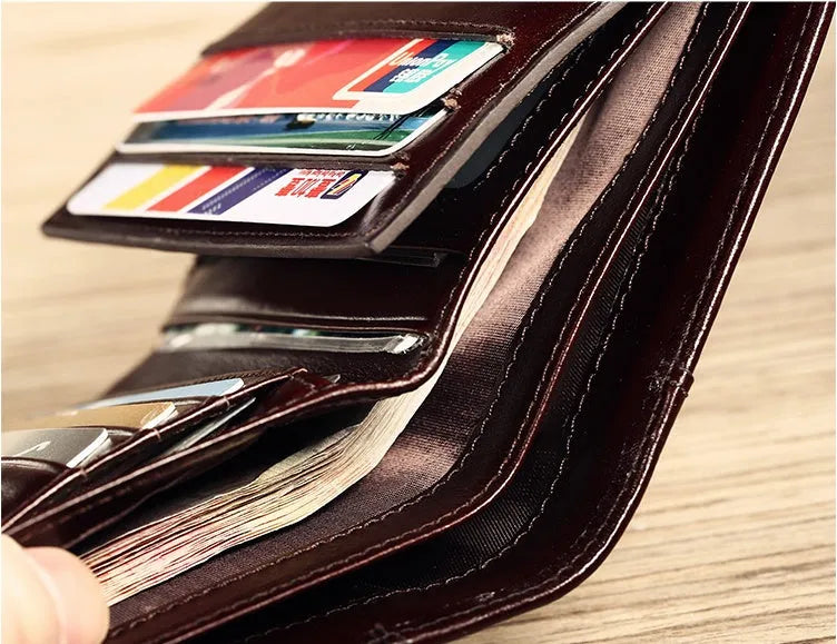 Men's black leather bifold wallet open to show internal card slots, photo window, coin pocket, and banknote compartment.