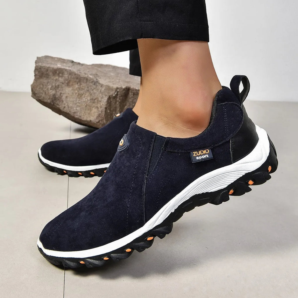 Men's grey slip-on shoe cover with round toe and rubber sole on a white background.