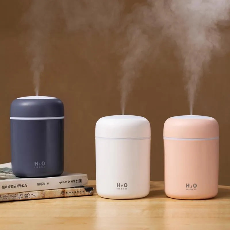 Pink USB desktop humidifier with coloured lights and water tank on a wooden desk