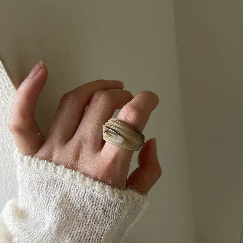 Geometric irregular resin wide ring in brown and white colours on a plain background.