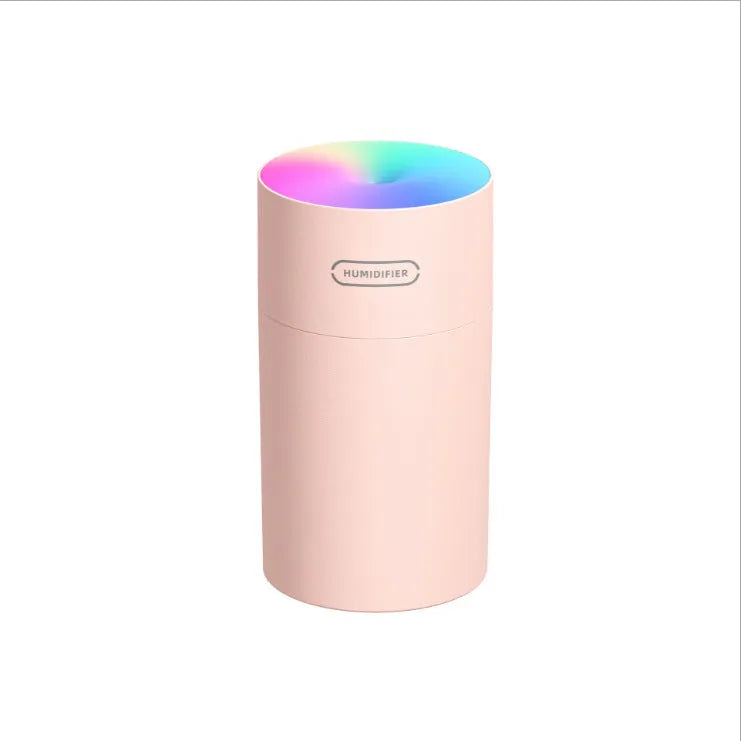 Pink USB desktop humidifier with coloured lights and water tank on a wooden desk