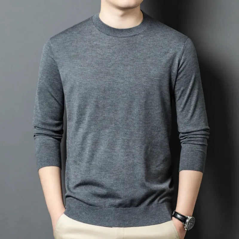 Man wearing a round neck grey wool blend sweater with long sleeves.